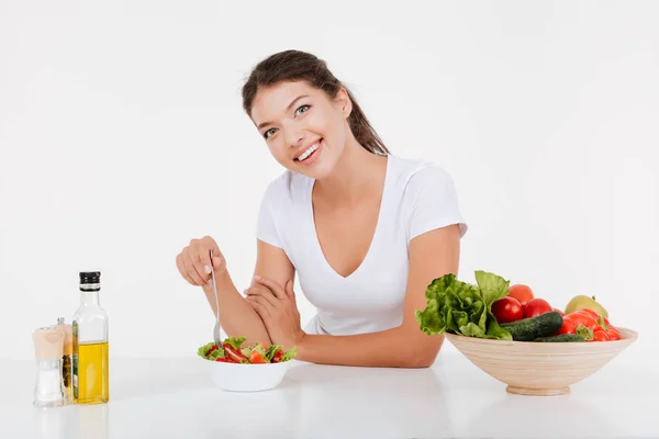 Felice giovane signora cucina e mangiare insalata di verdure — Foto Stock