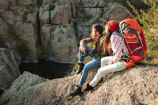 Приключенческая пара, сидящая на камне — стоковое фото