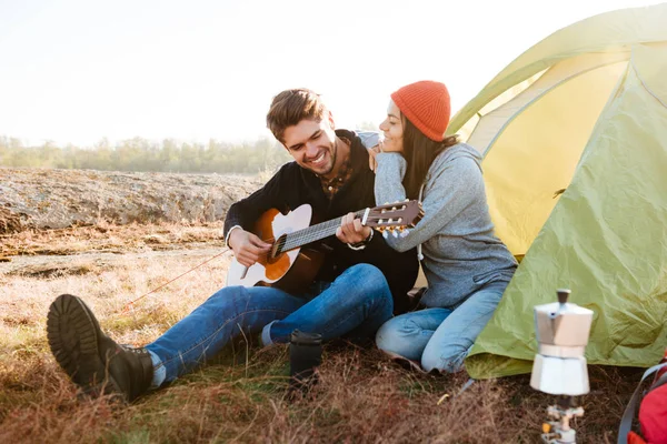 Gitározni a barátnője a sátorban ül az ember — Stock Fotó