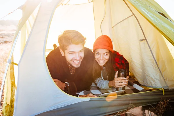 Lachende paar in de tent liggen en het gebruik van tablet pc — Stockfoto