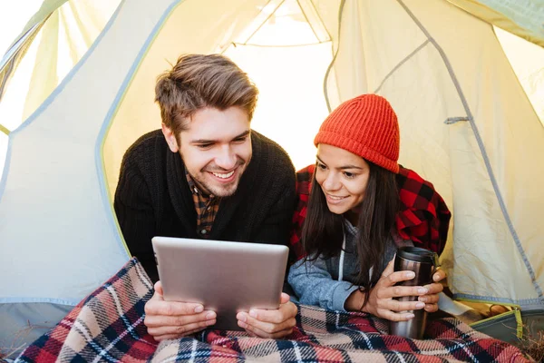 Glückliches Paar liegt im Zelt und nutzt Tablet-Computer — Stockfoto