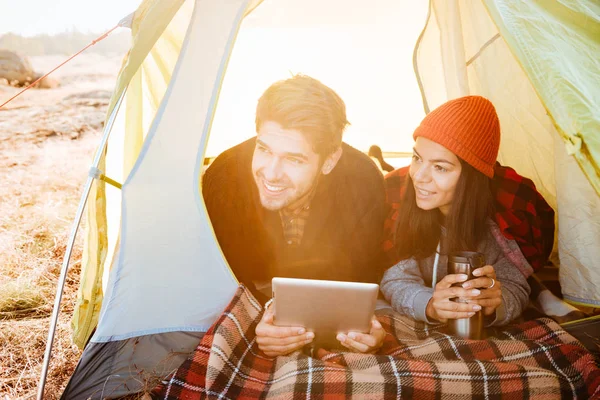 Coppia sorridente sdraiata in tenda e utilizzando tablet — Foto Stock