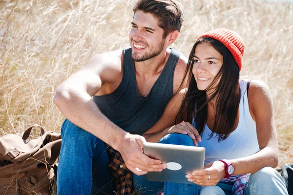 Gelukkige paar zitten met tablet terwijl het hebben van een kamp — Stockfoto