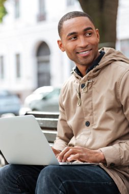 Bankta oturan ve tipik dizüstü bilgisayar ile Afrika delikanlı