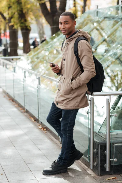 Jovem africano feliz segurando seu telefone nas mãos — Fotografia de Stock