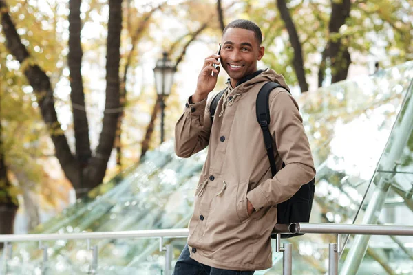 Jovem africano com mochila falando ao telefone na rua — Fotografia de Stock