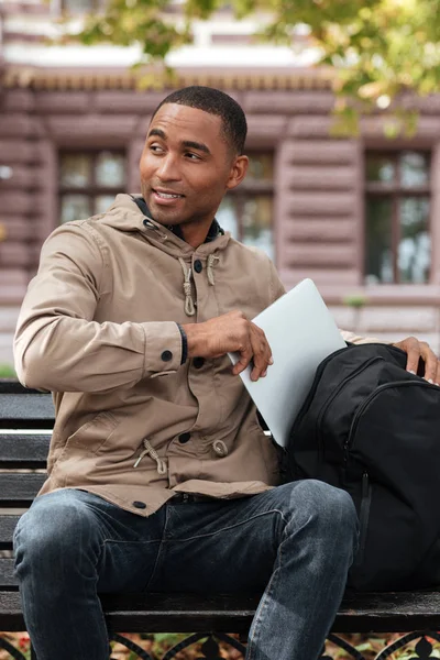 Jovem homem africano alegre recebendo laptop de mochila — Fotografia de Stock