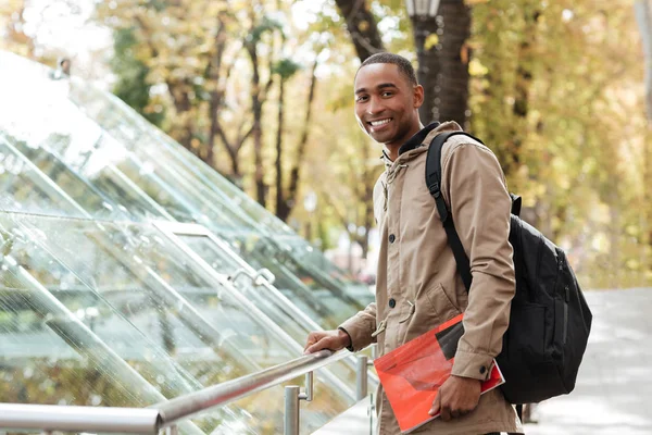 Africano usando mochila de pé na rua com livro — Fotografia de Stock