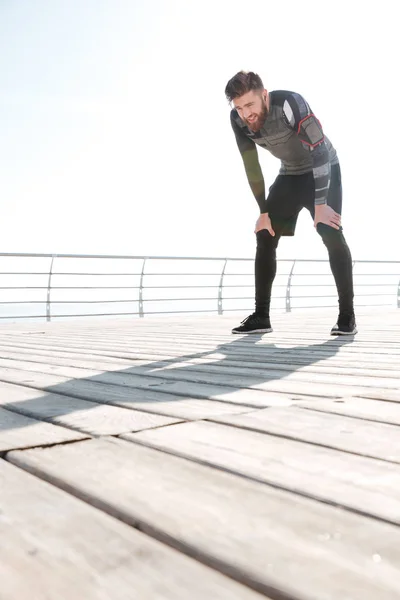 Tired young runner near the sea