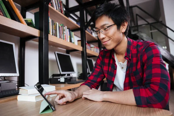Asiático masculino usando tablet na biblioteca — Fotografia de Stock