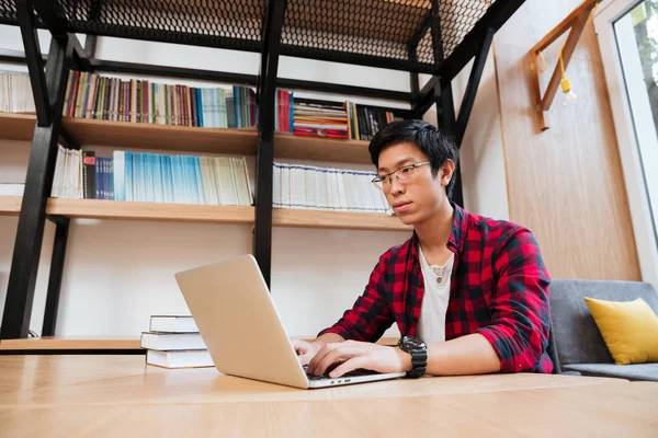 Asiático masculino usando laptop na biblioteca — Fotografia de Stock