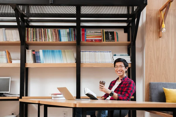 Männchen benutzt Laptop beim Lesen von Büchern und Kaffeetrinken — Stockfoto