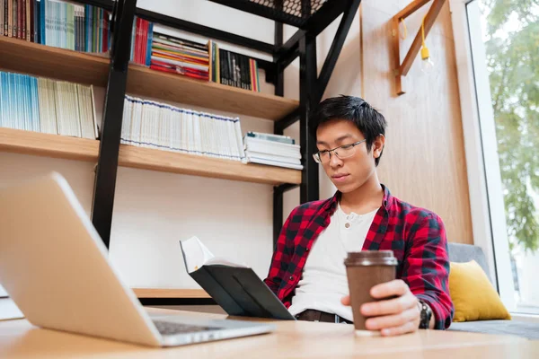 Man använder laptop samtidigt läsa bok och håller kaffe — Stockfoto