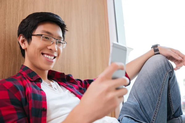 Glad asiatisk student chattar i Universitetsbiblioteket sitter på soffa — Stockfoto