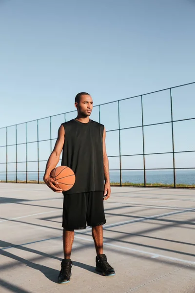 Konsentrat atraktif olahragawan memegang basket saat berdiri di taman bermain — Stok Foto