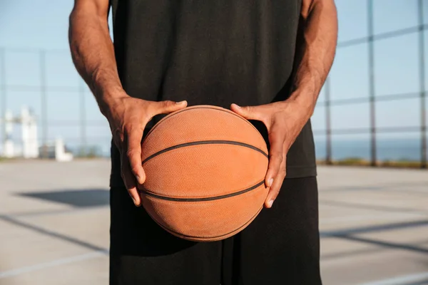 Retrato de mãos masculinas segurando basquete com playground no fundo — Fotografia de Stock