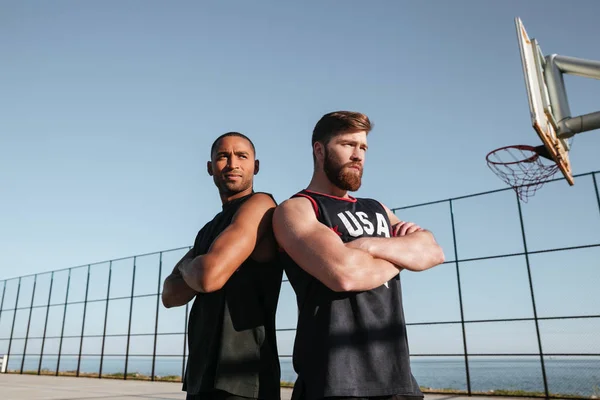 Dos jugadores de baloncesto de pie en el playgroud con los brazos cruzados — Foto de Stock