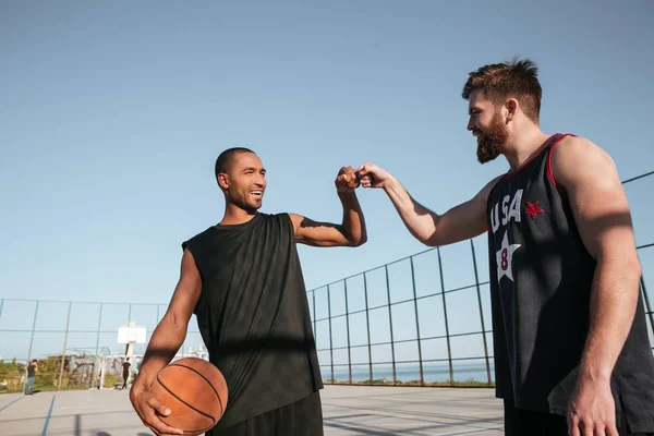 Dos deportistas felices golpeando el puño antes de comenzar el juego de baloncesto — Foto de Stock