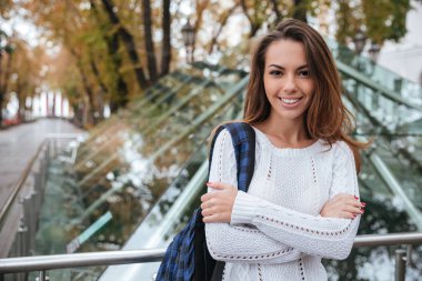 Gülümseyen genç kadın kolları ile ayakta şehirde geçti