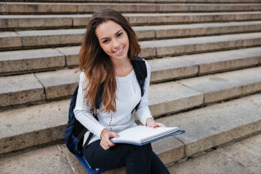 Sırt çantası ve açık havada merdivenlerde oturan noteped mutlu kadınla