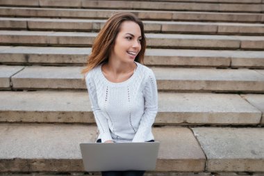 Mutlu bir kadın smilign ve dizüstü merdiven kullanma