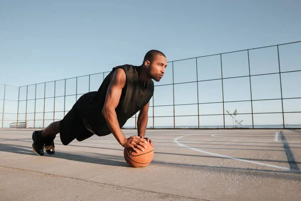 Hombre deportivo haciendo ejercicio de tablón con pelota en el patio de recreo — Foto de Stock