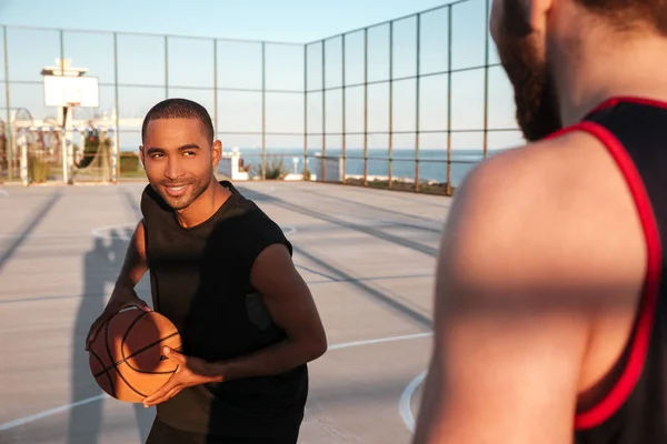 Sonriente atleta afroamericano jugando baloncesto con su amigo — Foto de Stock