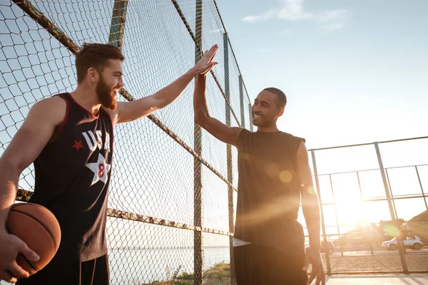 Deportistas dando cinco altos mientras juegan baloncesto en el patio de recreo — Foto de Stock