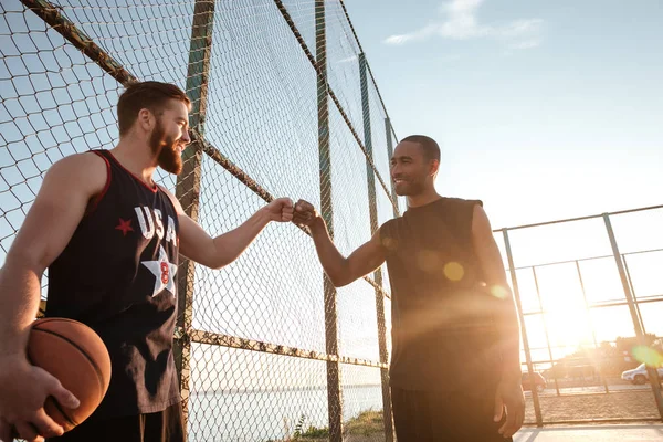 Dos deportistas felices golpeando el puño antes de comenzar el juego de baloncesto — Foto de Stock