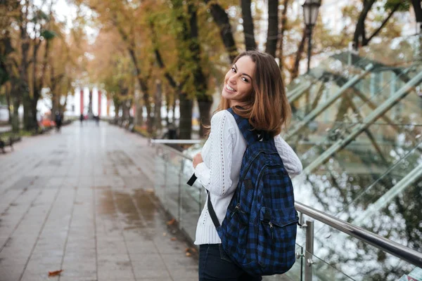 Back view of happy woman with backpack walking in park — Stock Photo, Image