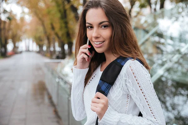 Счастливая красивая молодая женщина разговаривает по мобильному телефону в парке — стоковое фото