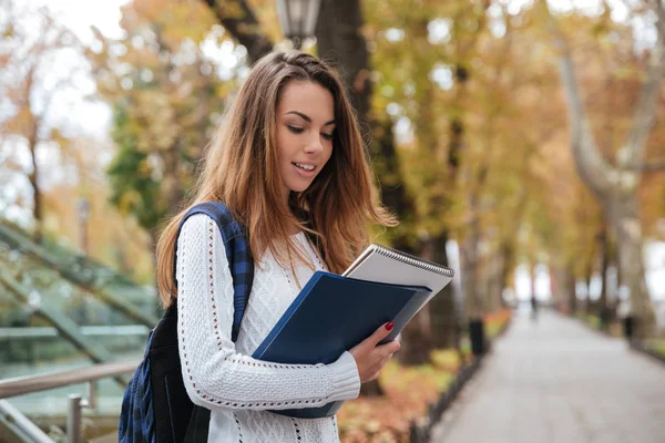 Vrouw met rugzak en notebooks wandelen in het park — Stockfoto