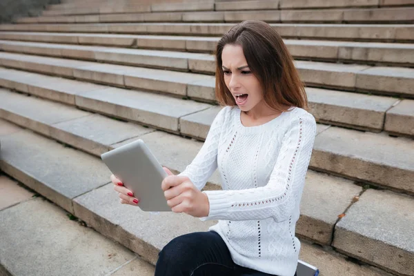 Merdivenlerde oturan ve tablet kullanarak kızgın kadın — Stok fotoğraf