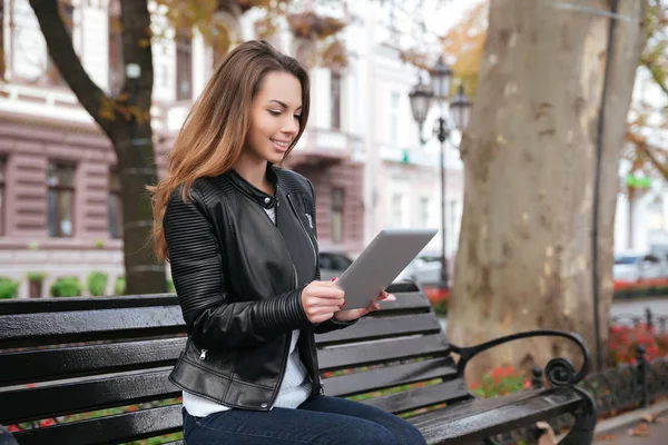 Kadın oturuyor ve parkta bankta tablet kullanma — Stok fotoğraf