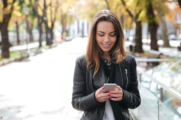 Mulher feliz andando e usando telefone celular na cidade — Fotografia de Stock