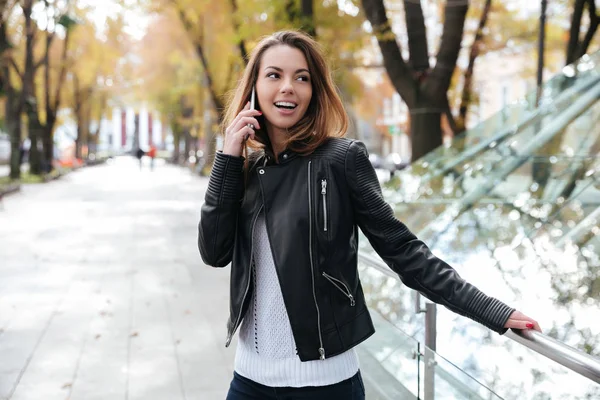 Sorrindo mulher de pé e falando no telefone celular no parque — Fotografia de Stock