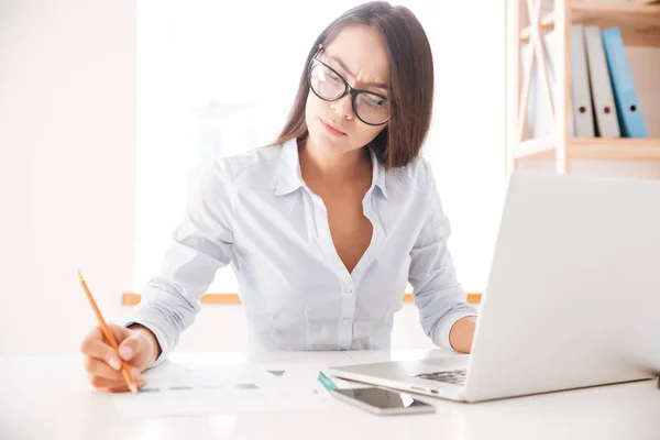 Zakenvrouw zitten in haar kantoor en schrijven van notities — Stockfoto