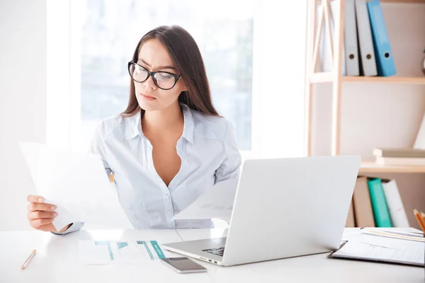 Mujer de negocios usando el ordenador portátil mientras mira los documentos — Foto de Stock