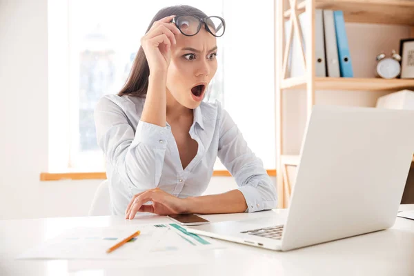 Junge Geschäftsfrau im weißen Hemd schockiert beim Öffnen eines Laptops — Stockfoto