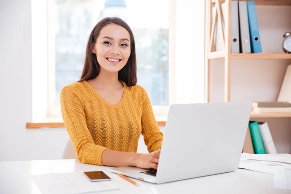 Cheerful businesswoman using laptop and looking at camera — Stock Photo, Image