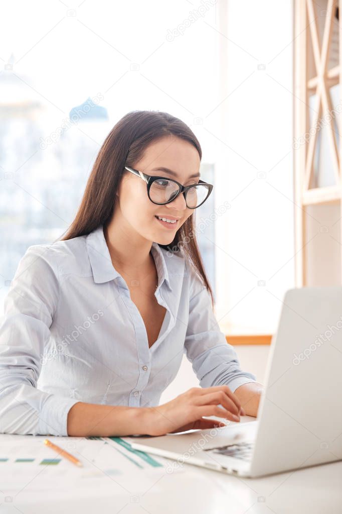 Businesswoman sitting in her office and using laptop.