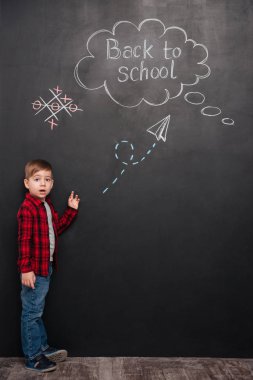 Çizim ile kara tahta üzerinde duran sürpriz küçük öğrenci