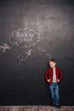 Sevimli öğrenci okuldan ile kara tahta arka plan üzerinde duran