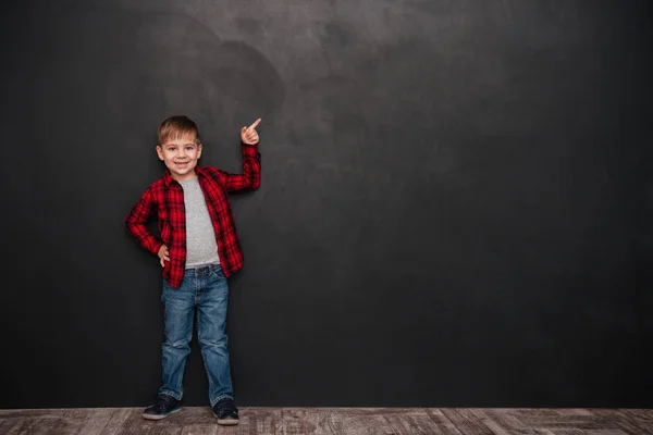Schattige kleine jongen zich bevindt over schoolbord en omhoog — Stockfoto
