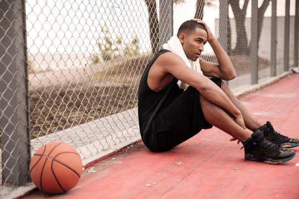 Jugador de baloncesto cansado sentado en el parque con toalla —  Fotos de Stock