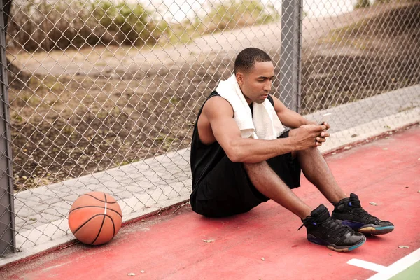 Joven jugador de baloncesto africano cansado sentado y charlando — Foto de Stock