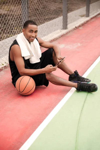 Afrikai kosárlabda játékos ül a parkban, és a gazdaság tabletta — Stock Fotó
