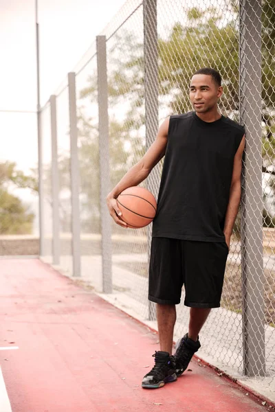 Jugador de baloncesto africano de pie en el parque mientras mira a un lado — Foto de Stock