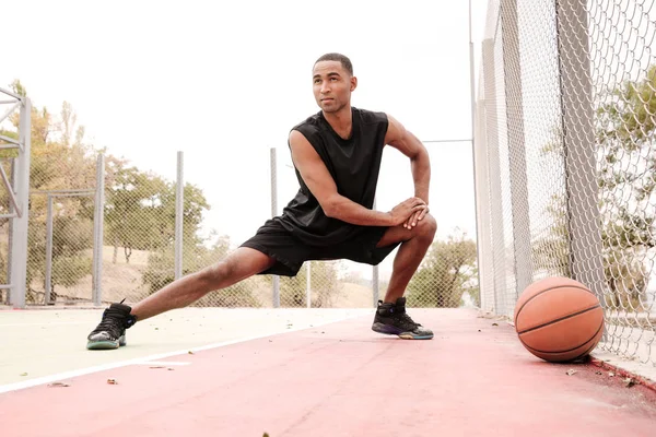 Jovem jogador de basquete concentrado fazendo exercícios esportivos — Fotografia de Stock