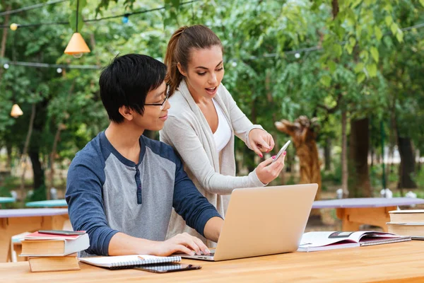 Student met laptop en mobiele telefoon in outdoor cafe — Stockfoto